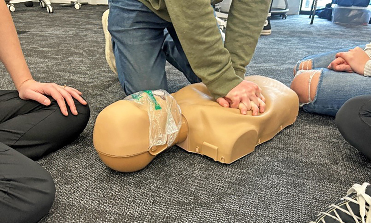 Students performing compressions on cpr model.