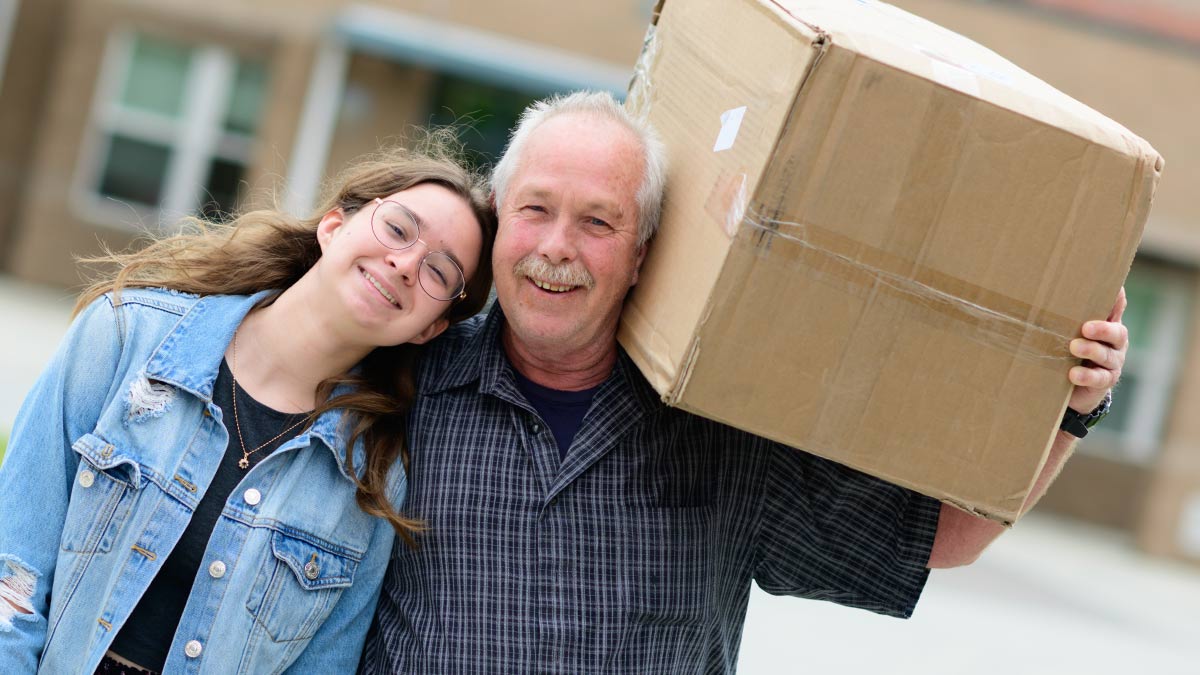 A student with their father holding a box
