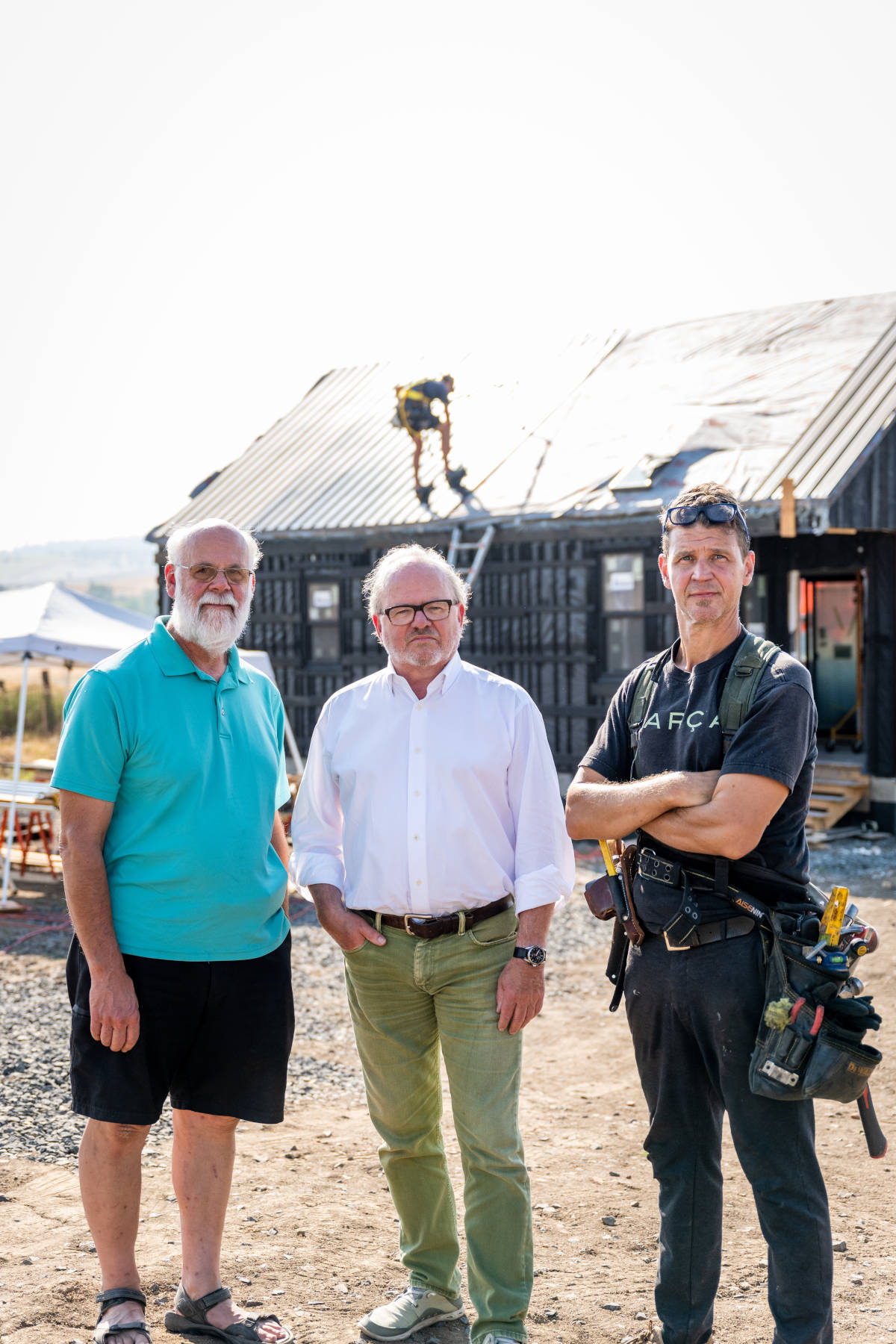 Three people standing in front of house construction.