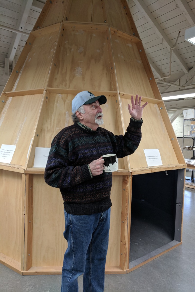 Bruce Haglund stands in front of the Daylighted Artificial Sky, a large, wooden cone-like structure.