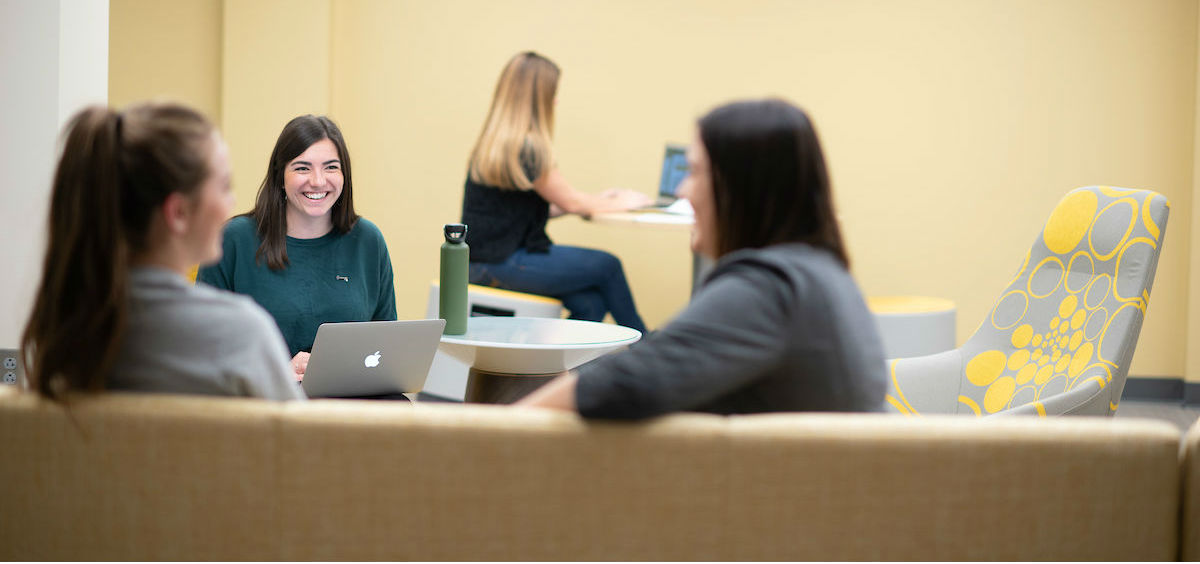 Students talk seated on new furniture in the Albertson basement.
