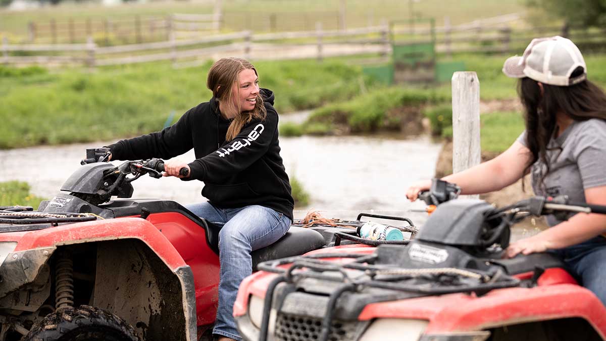 Two women sitting on ATV’s outside