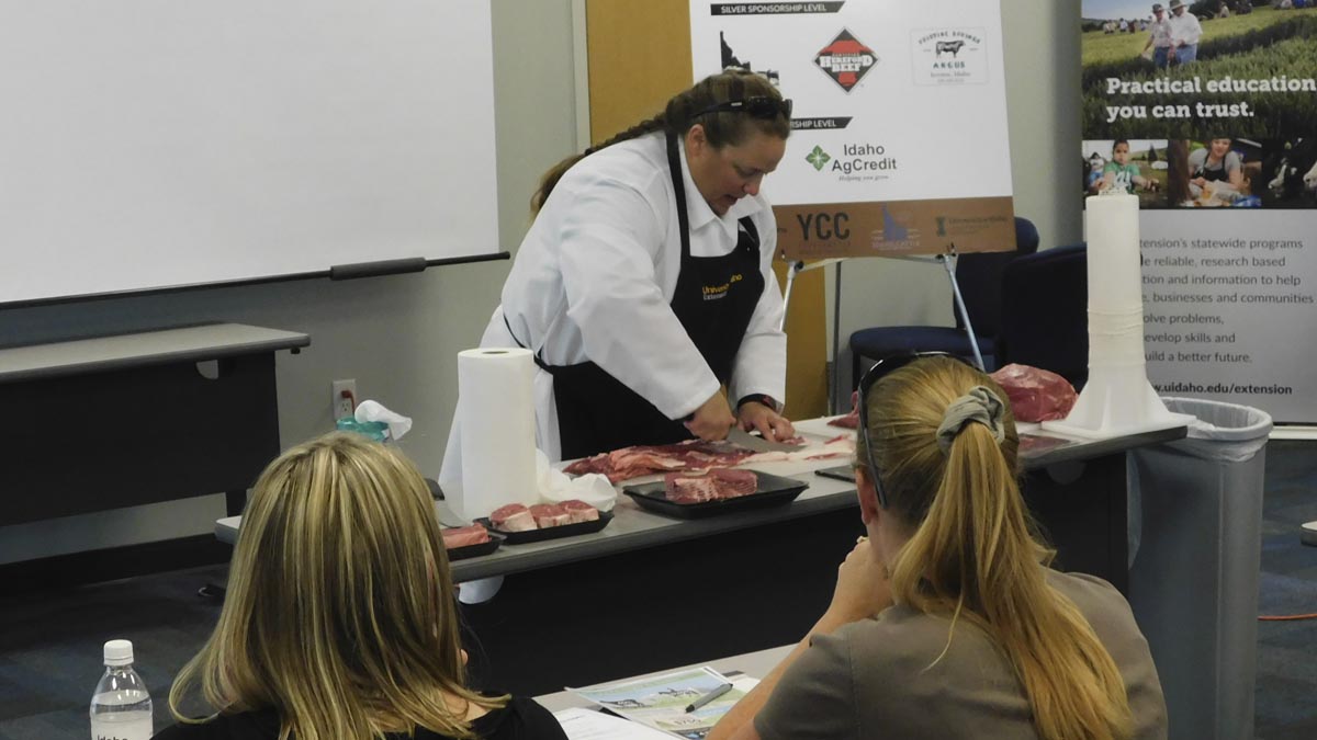 Woman cutting meat while others watch.