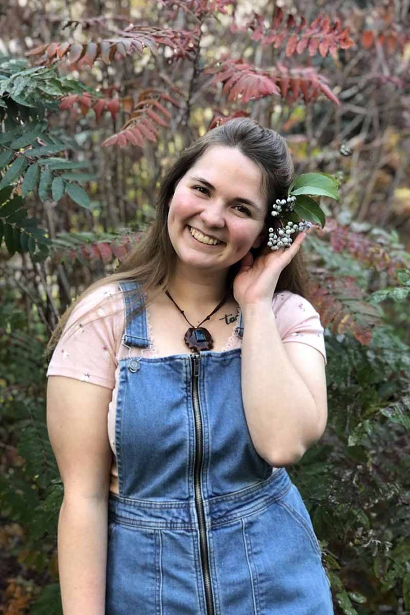 Woman standing in front of trees with flowers in her hair