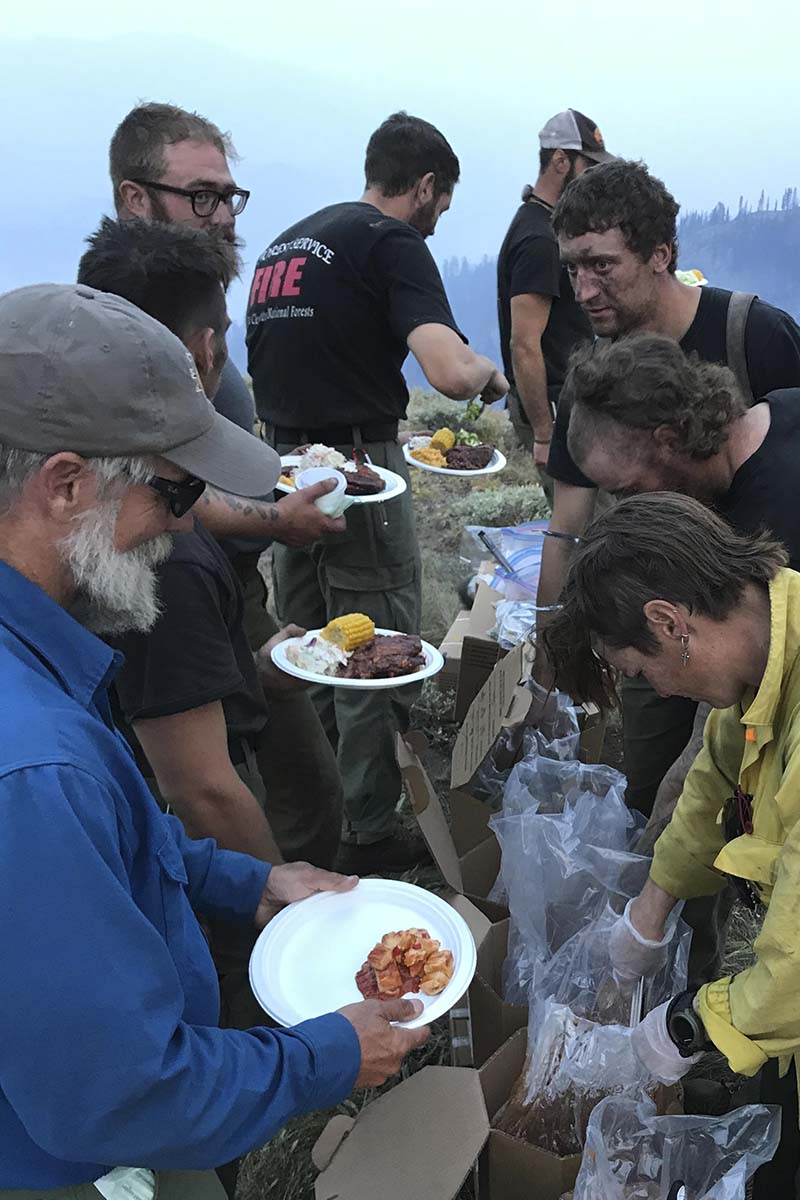 Firefighters stand in a chow line.