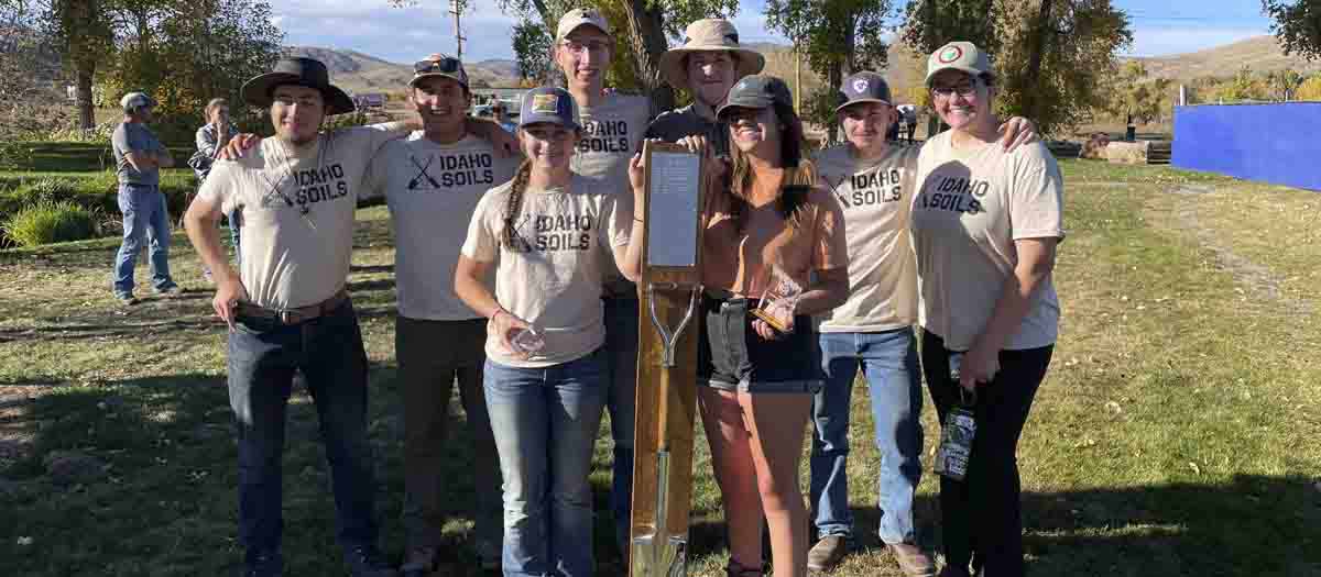 A group of students holding a shovel and an award.