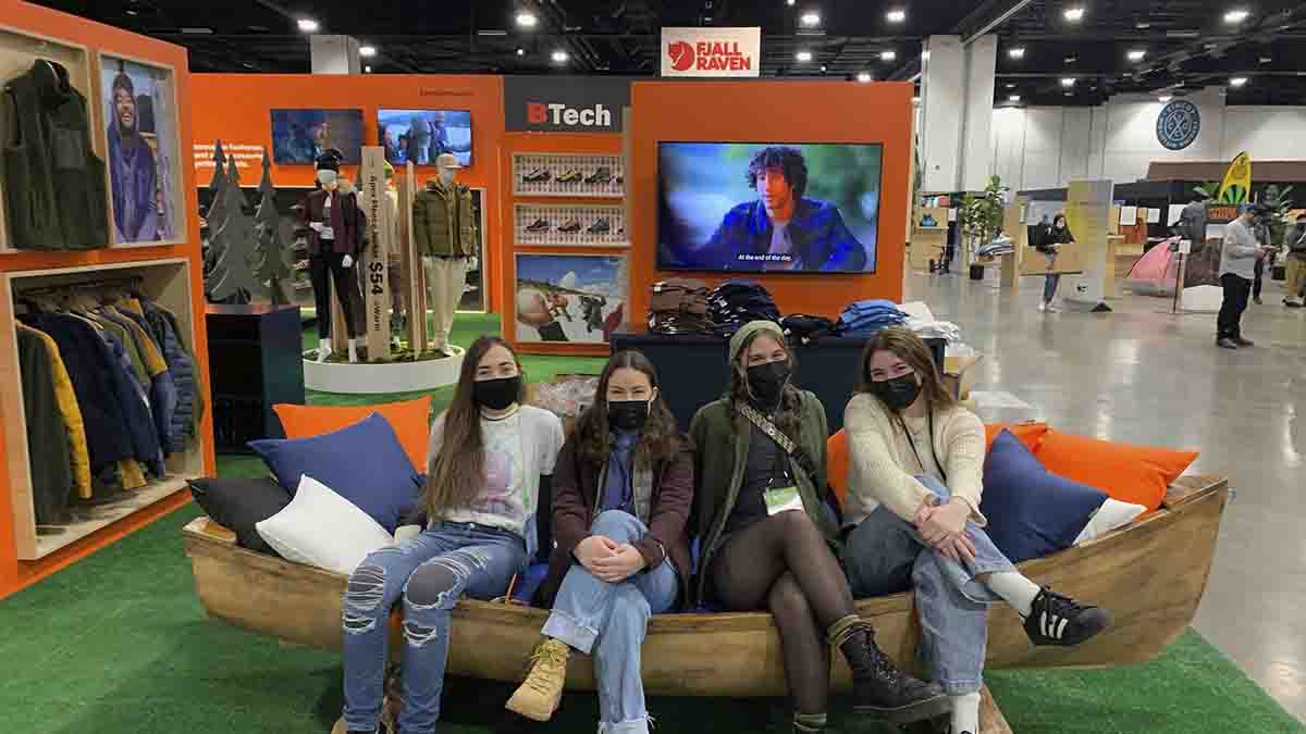 Four women sitting on a settee with displays behind them