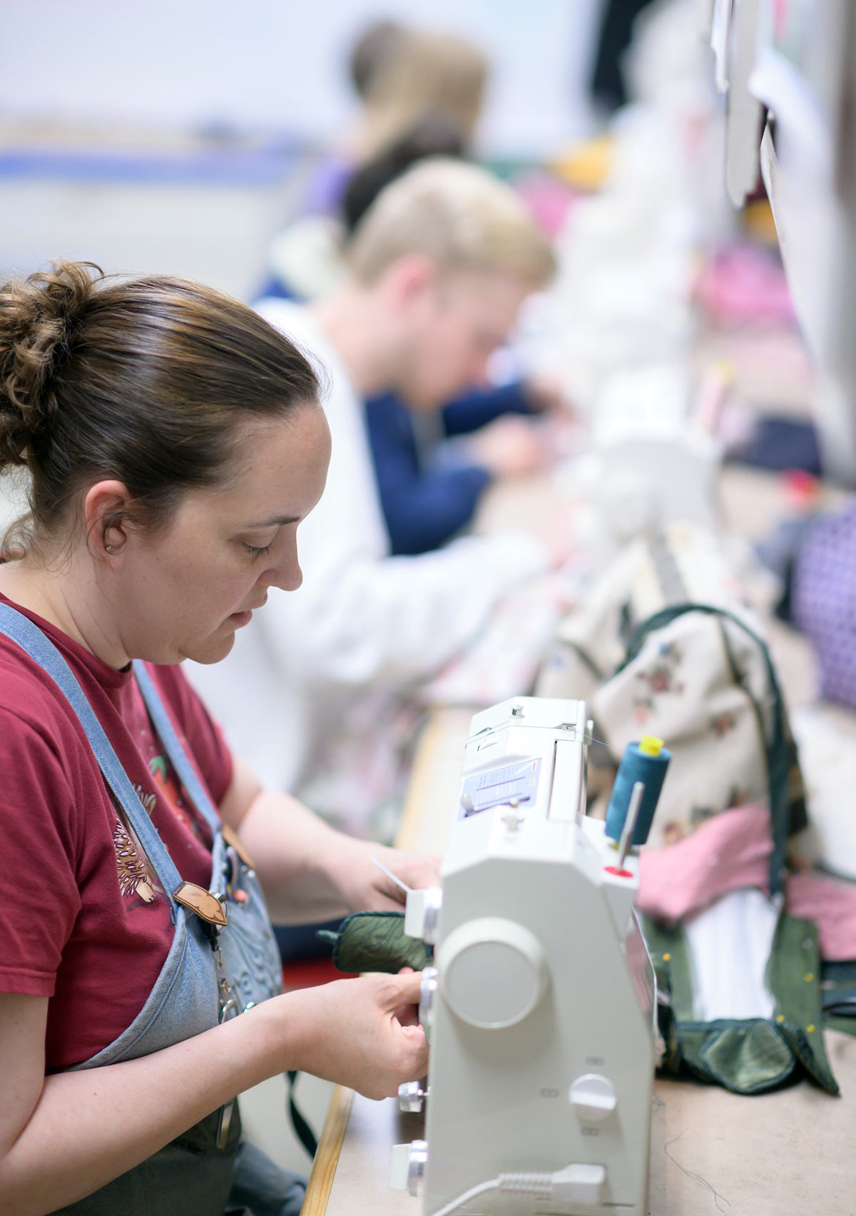 Ginger Sorensen sits at a sewing machine making costumes