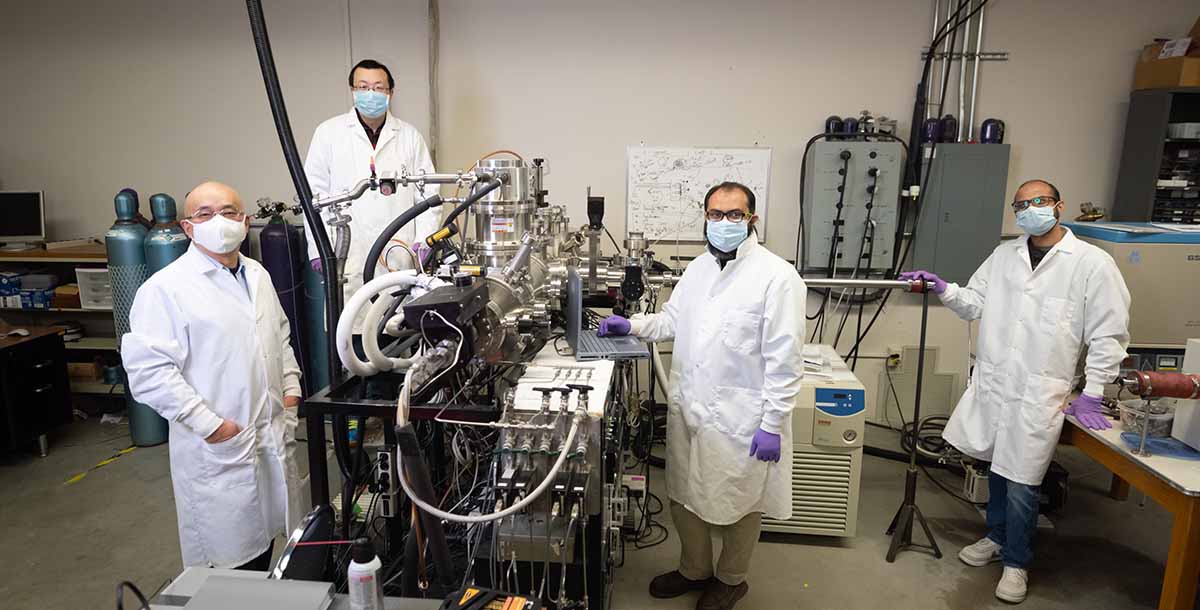 A group of science students gathers around a lab machine.