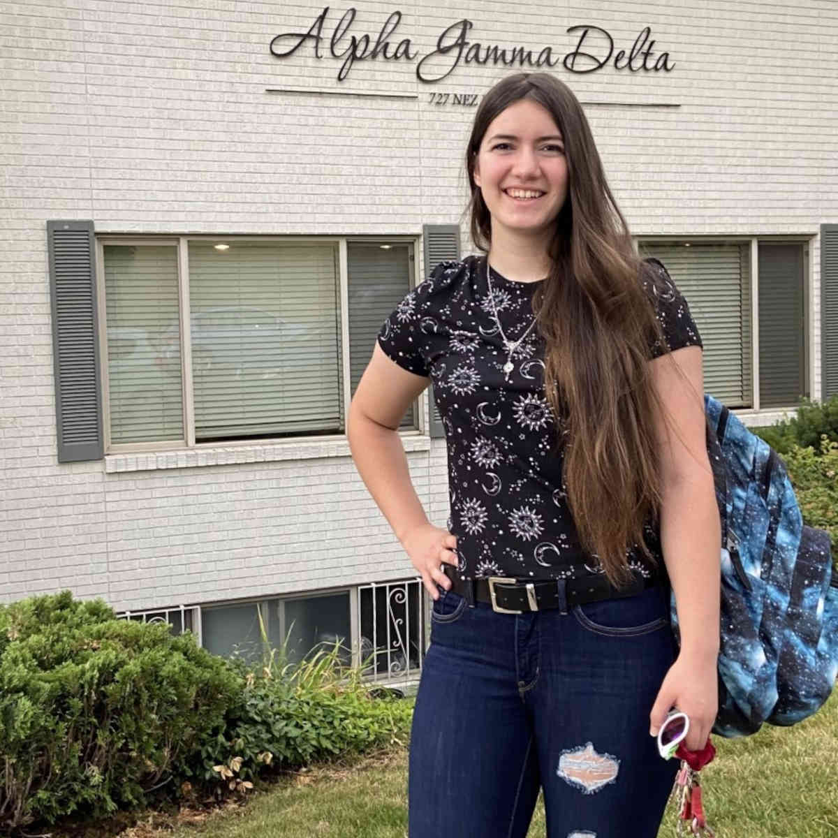 Jennie Tafoya standing in front of Alpha Gamma Delta building