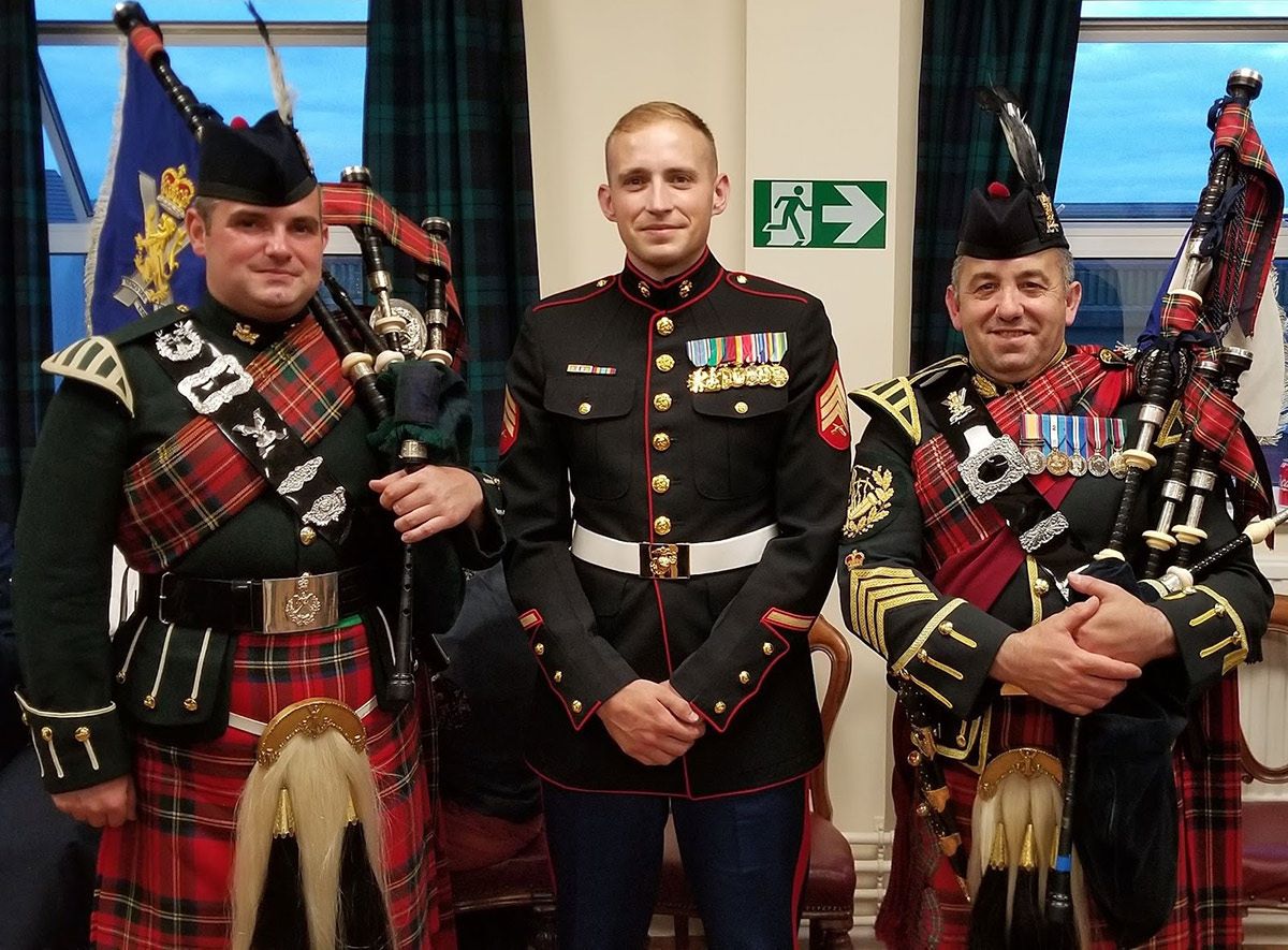 Logan Tompkins in military dress garb with bagpipers.