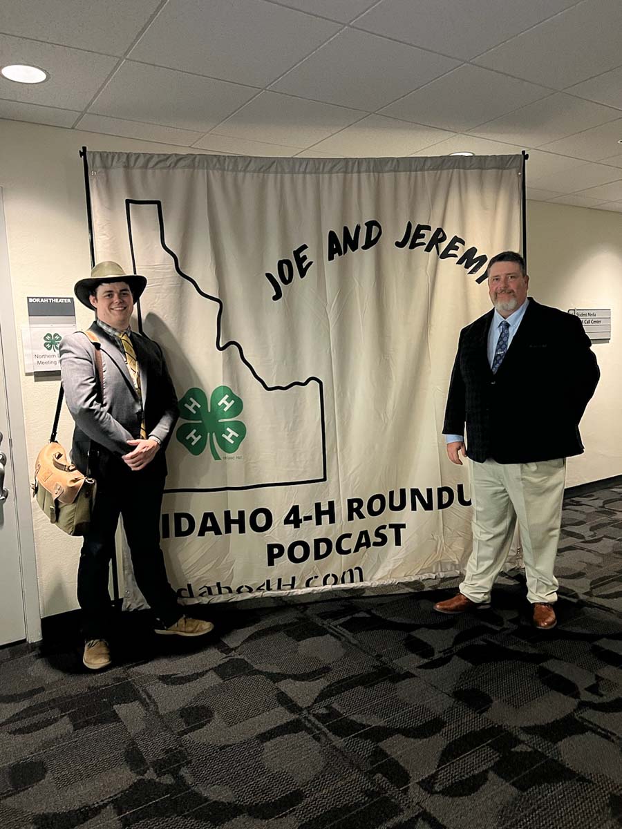 Two men stand in front of banner.