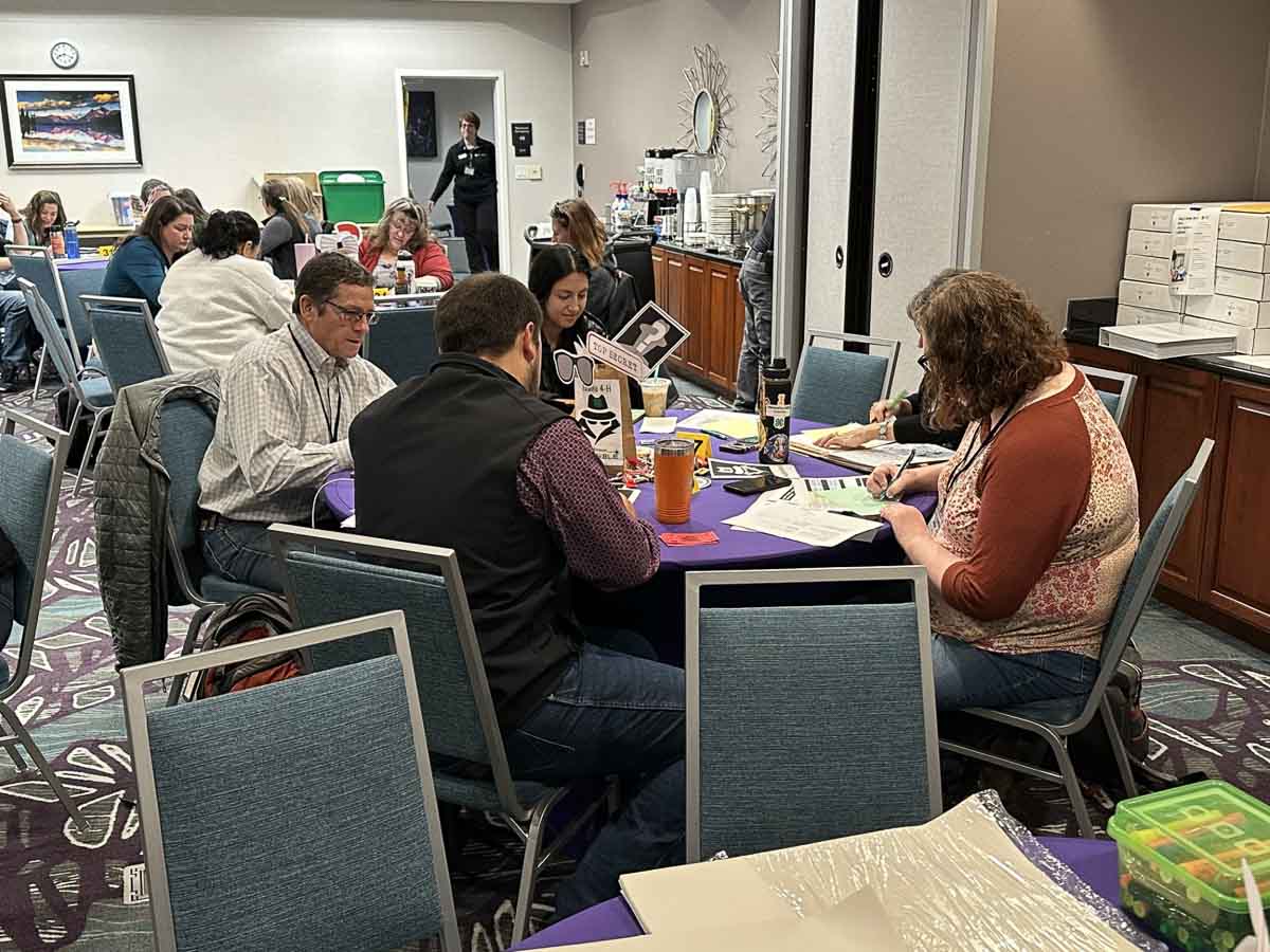 Group of adults do an activity around a table.