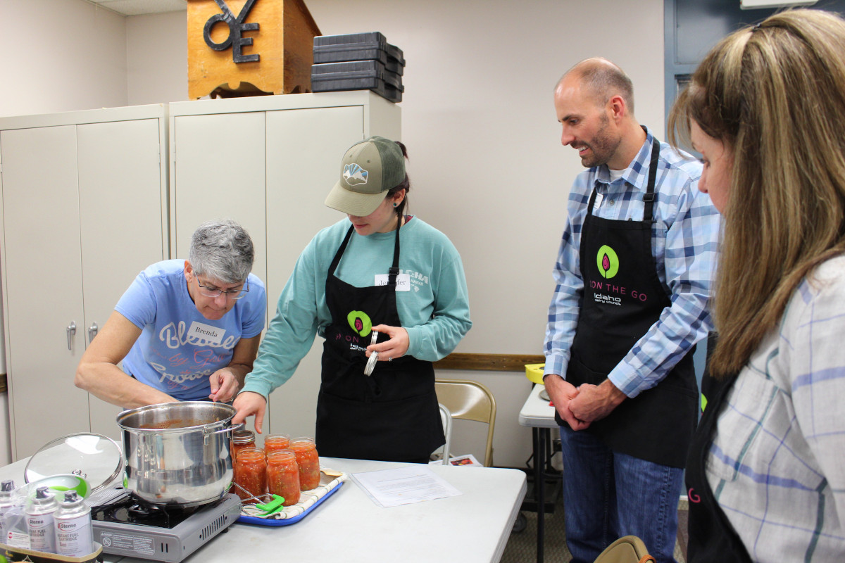 Participants of various ages watch a food canning demonstration.