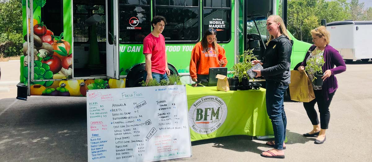Boise Farmer's Market table set up in front of the branded bus.