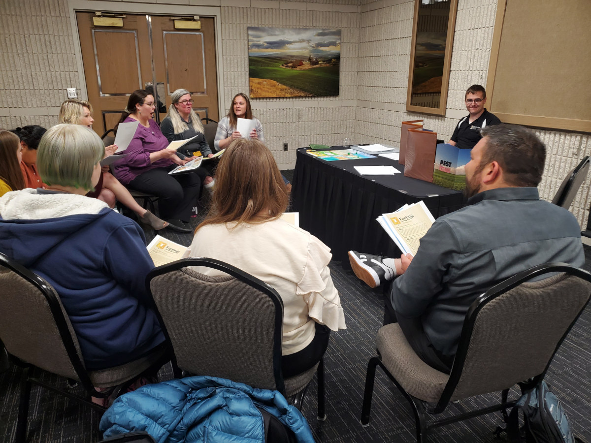 A group of adults discuss the Pest Friends board game.