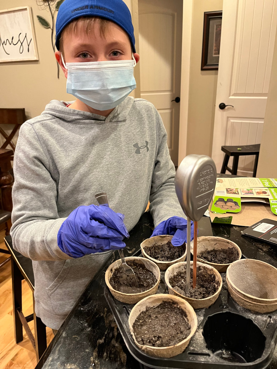 Young boy planting seedlings into fiber trays.