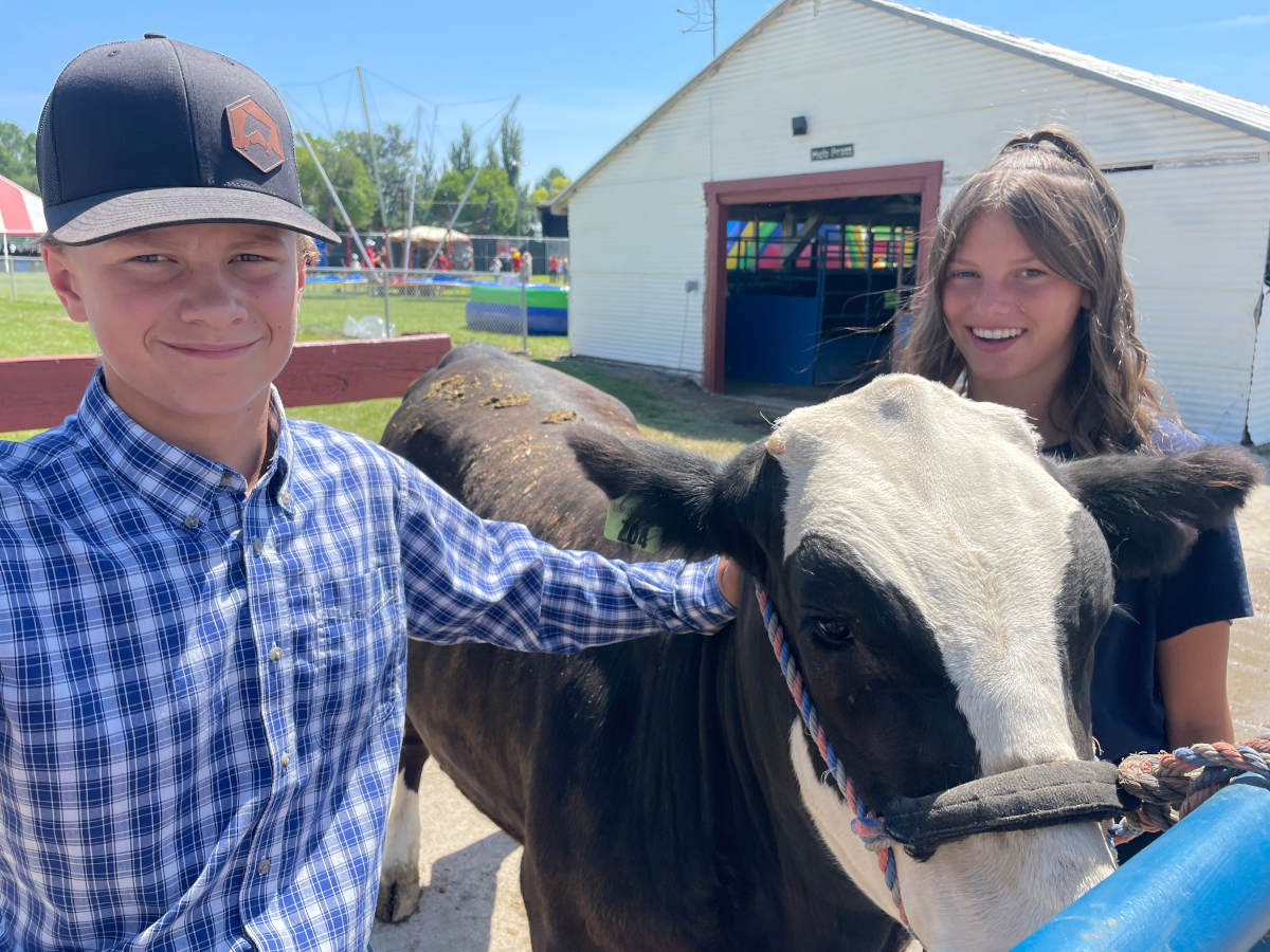 Two children next to a steer.