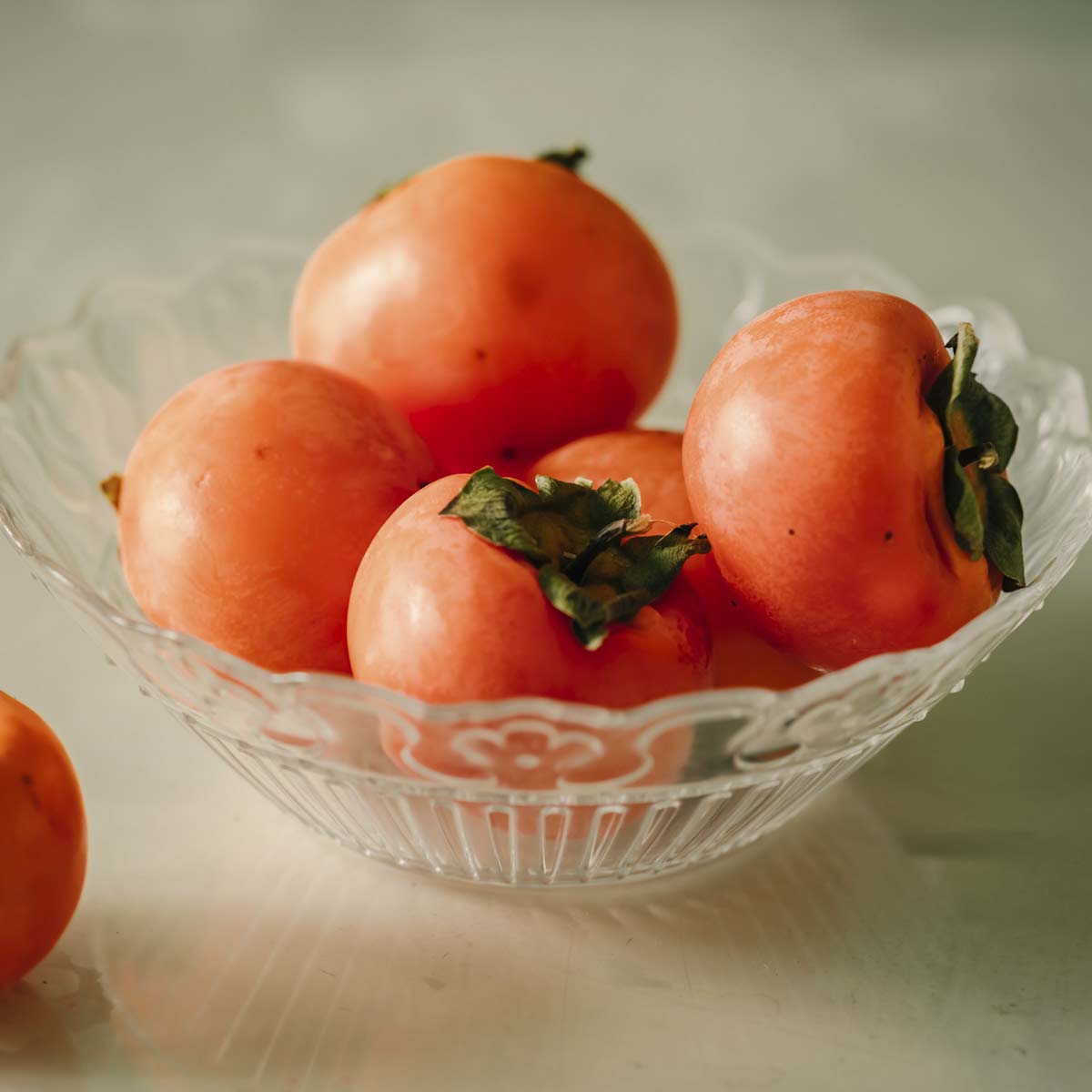 Ripe persimmon in glass bowl.