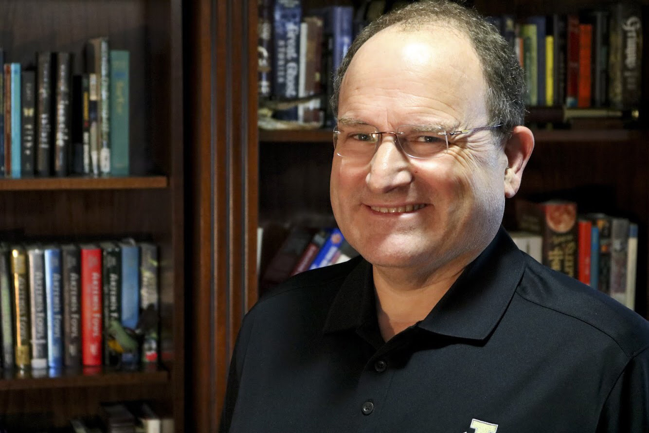 Mike McKellar in front of a bookcase.
