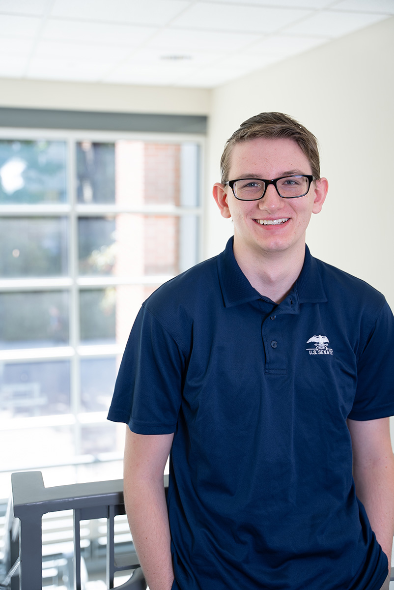 Young man smiling with glasses near stairwell.