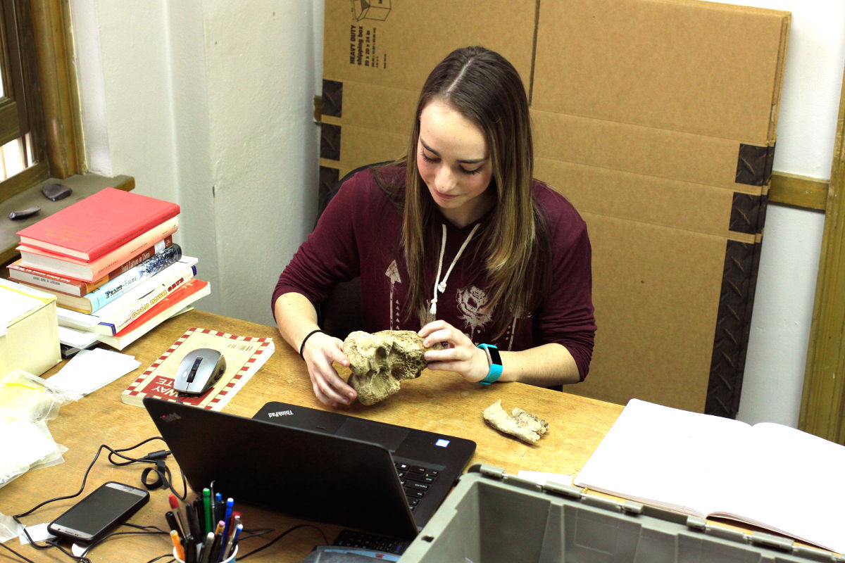 Chelsea Codling at her desk holding a bone.