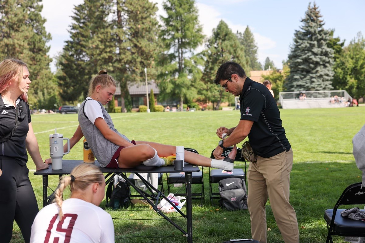 Man treating injury to woman lying on a table.