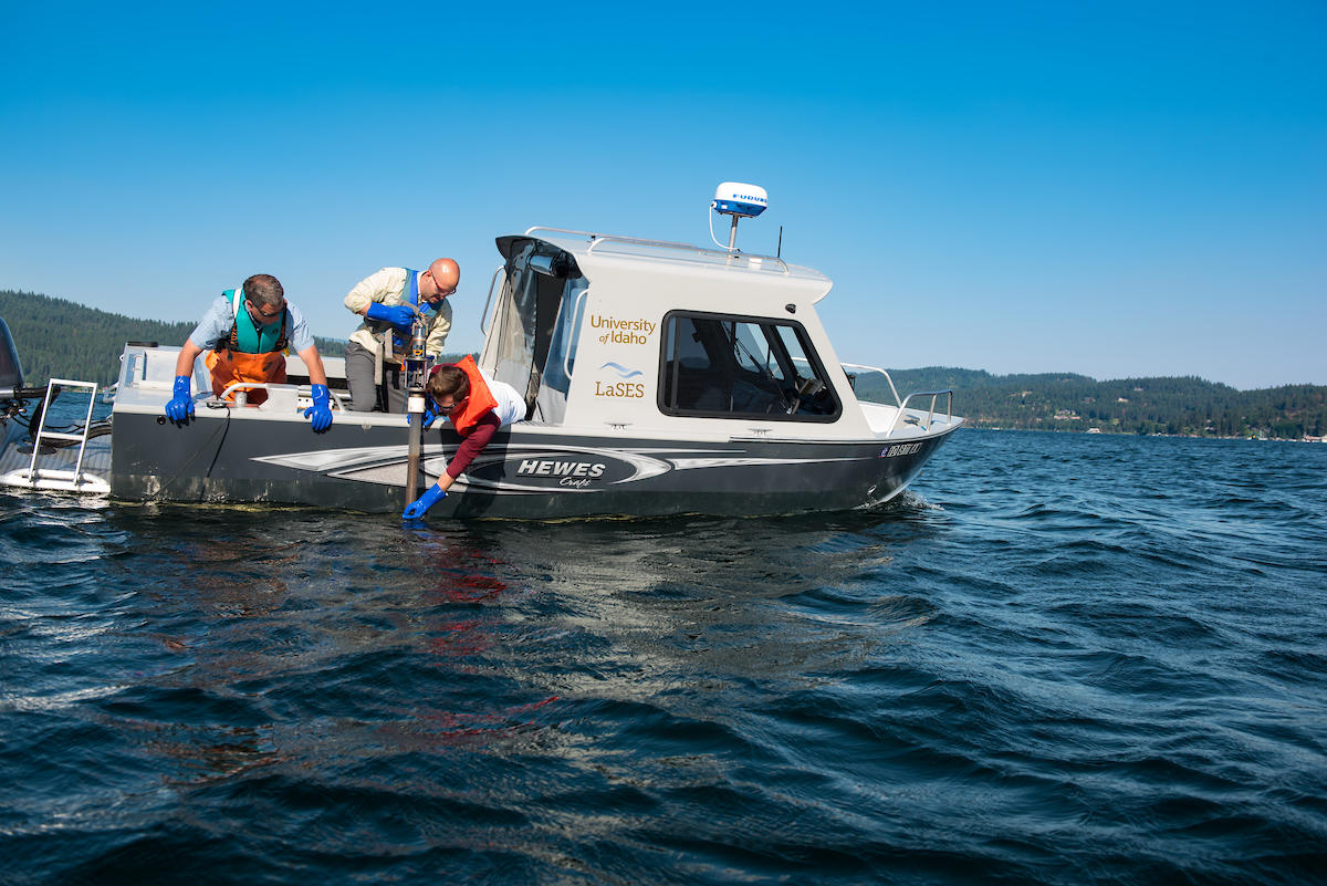 Scientists pulling up a sediment core sample over the side of the boat.