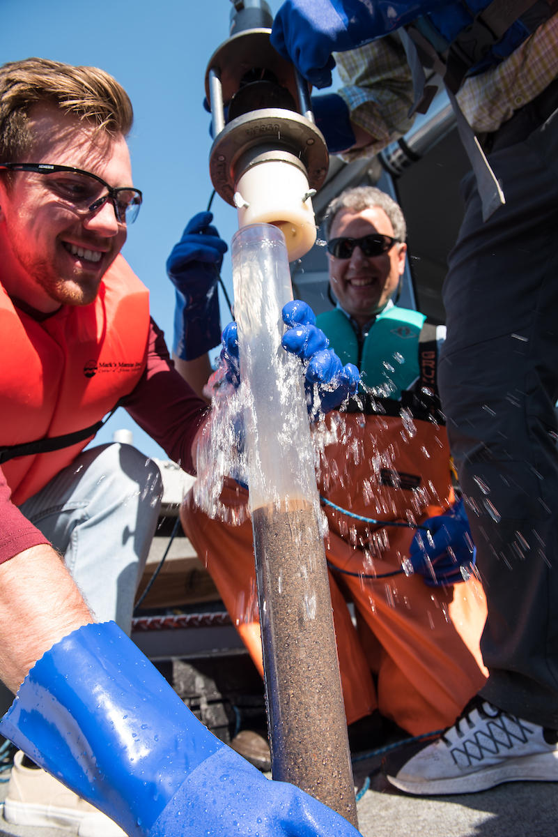 Kasey Peach holds a clear tube filled with sediment and lake water.