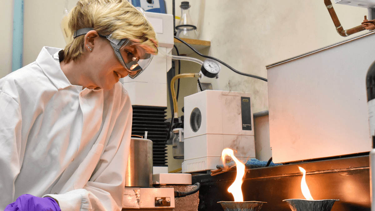 Murphy watches two metal pans of fuel burn.