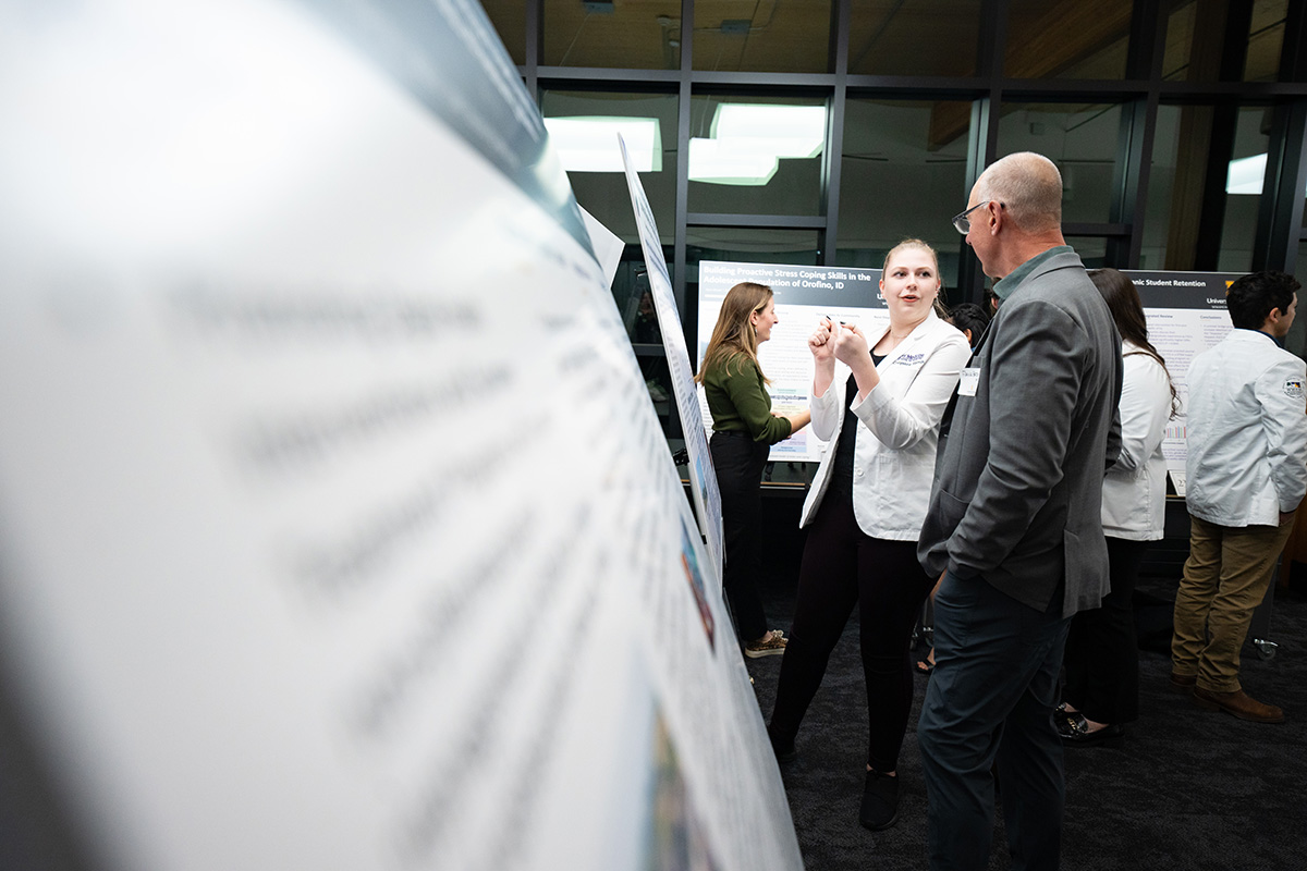 WWAMI student in white coat presenting her research project.