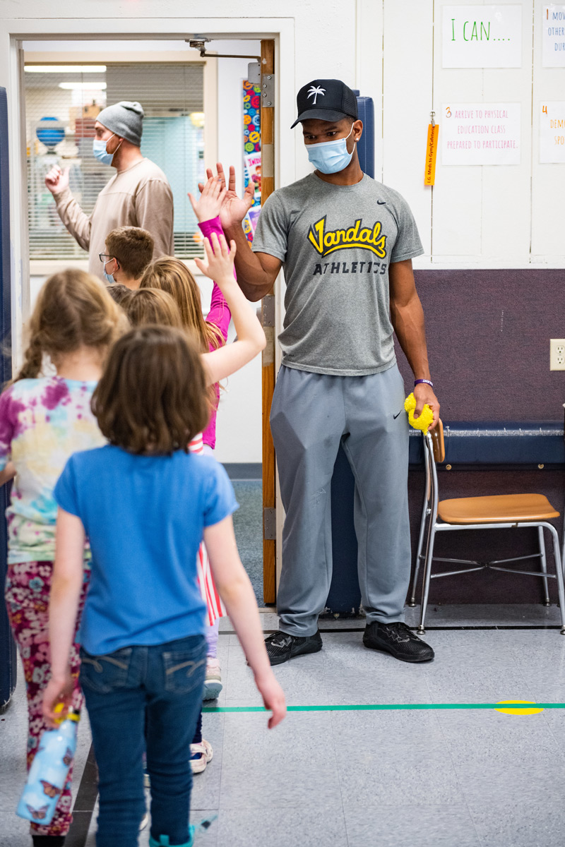 Wyryor stands at the classroom door giving high fives to elementary students as they leave his class.