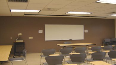 The whiteboard, seated desks, tables and projection equipment of LLC 132.