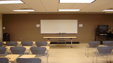 The whiteboard, seated desks, television, tables and projection equipment of LLC 133.